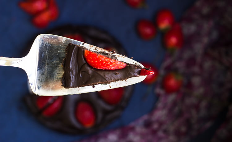 Close-up of a slice of no-bake chocolate strawberry tart with fresh strawberries on top