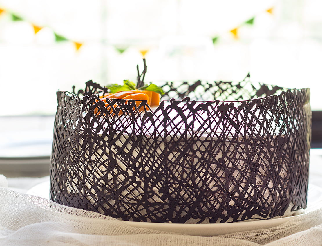 A whole eggless mango white cake placed on a plate, ready to be sliced