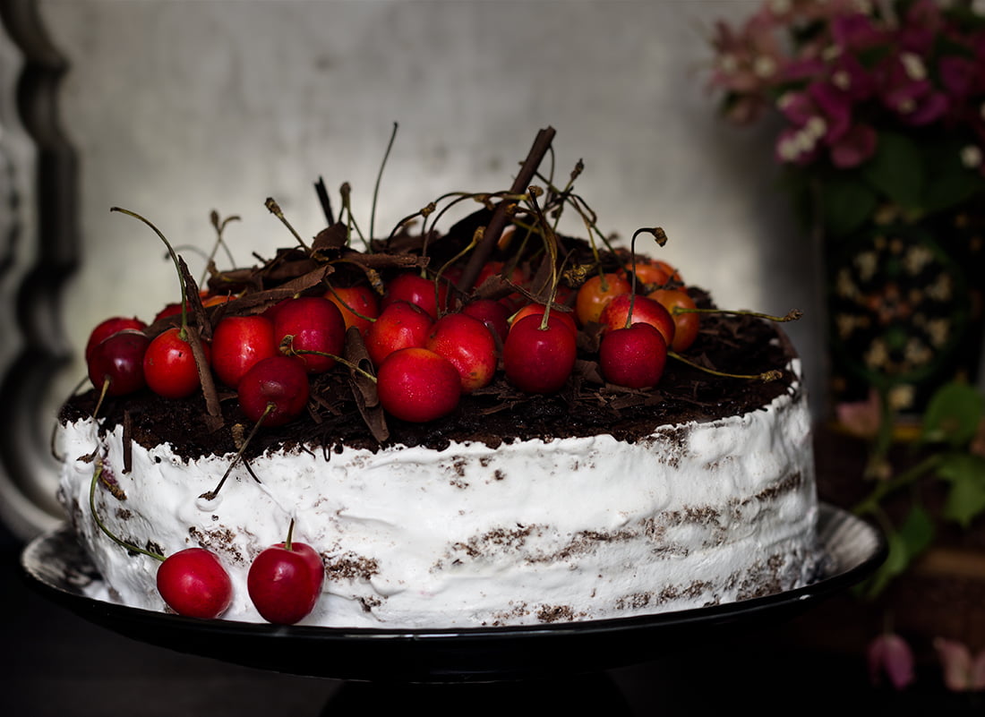 Whole eggless black forest cake decorated with chocolate shavings and cherries