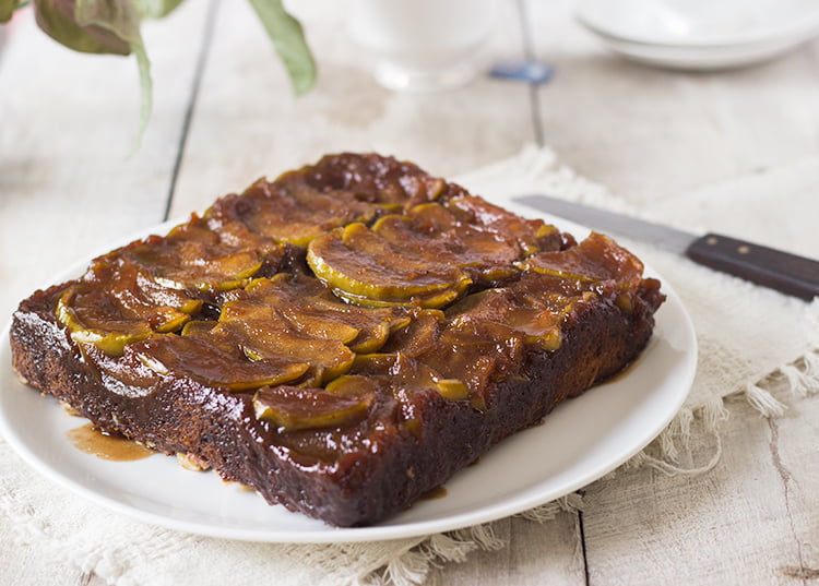 Sliced caramel apple upside-down cake on a white plate