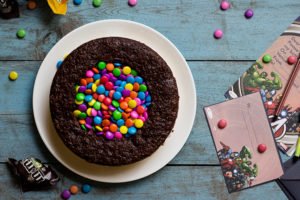 A beautifully decorated M&M Pinata Cake with a rainbow of M&Ms on top
