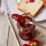 Thick strawberry jam cooling in a glass jar