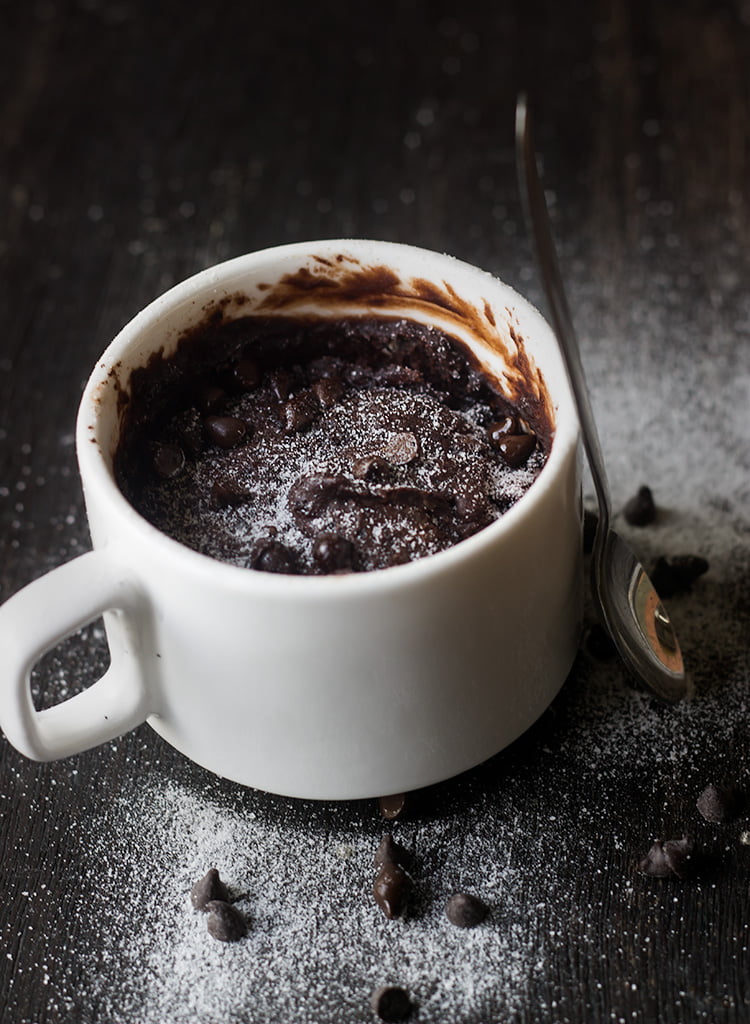 Close-up of gooey brownie in a white ceramic mug.