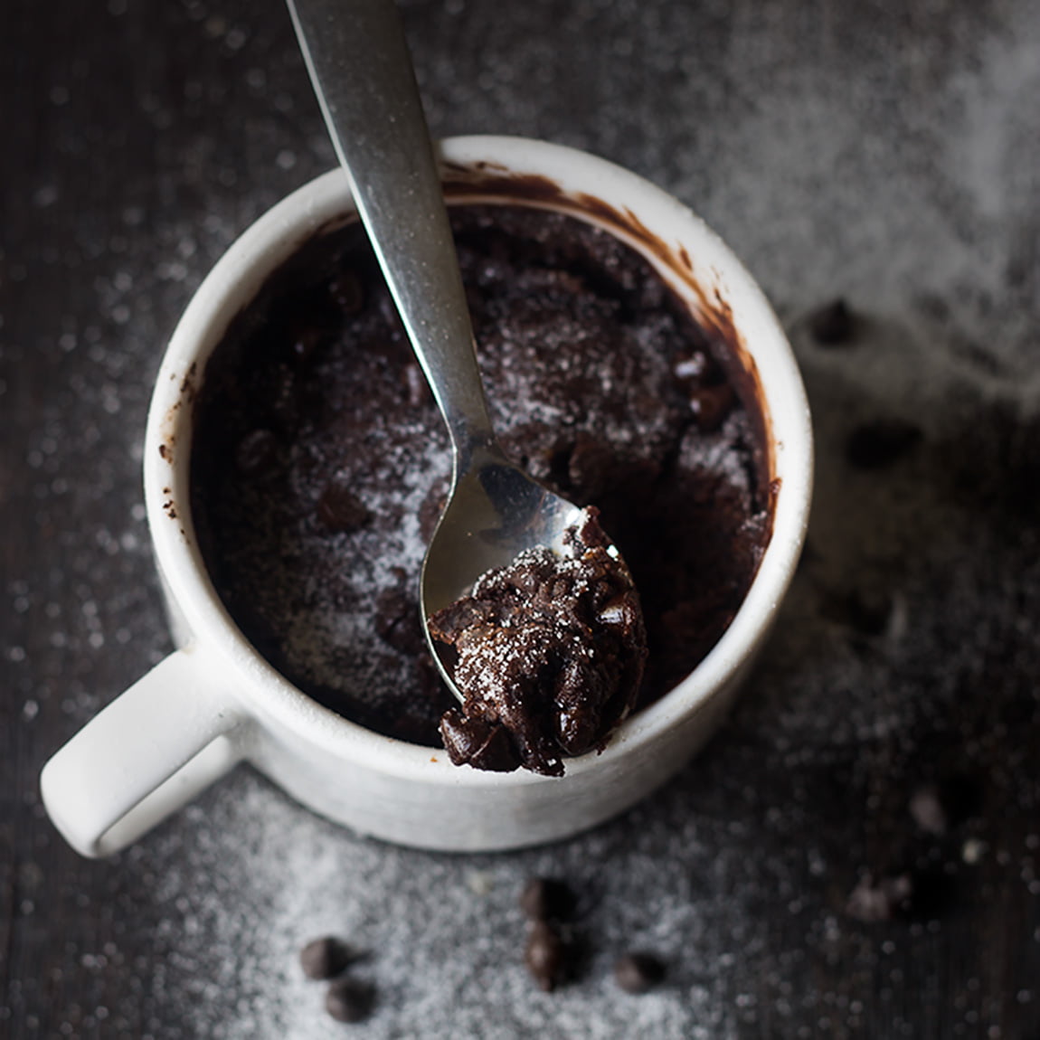 Close-up of gooey brownie in a white ceramic mug.