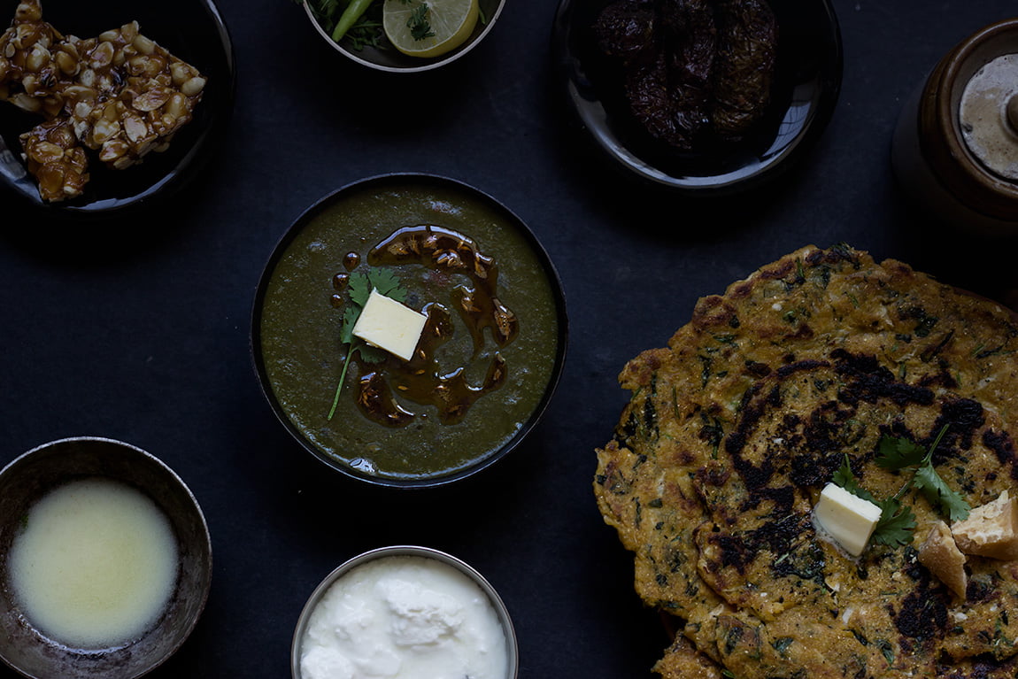 Freshly prepared Sarson Ka Saag with a dollop of white butter, surrounded by traditional Indian spices