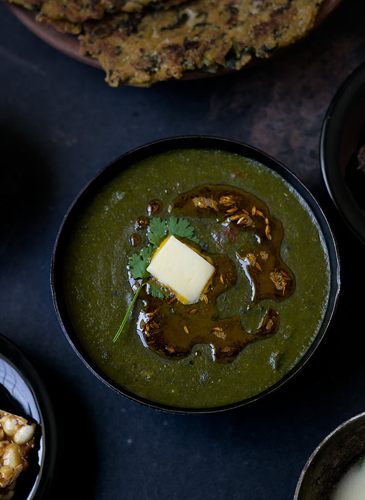 Close-up of Sarson Ka Saag in a bowl, garnished with butter and green chilies