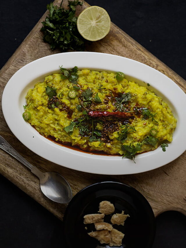 A plate full of Bajre Ki Khichdi garnished with fresh coriander and served with a side of yogurt