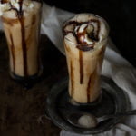 Close-up of an iced coffee frappe with a thick layer of whipped cream and chocolate syrup drizzling down the sides