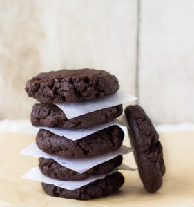 A stack of freshly baked double chocolate chip cookies on a cooling rack