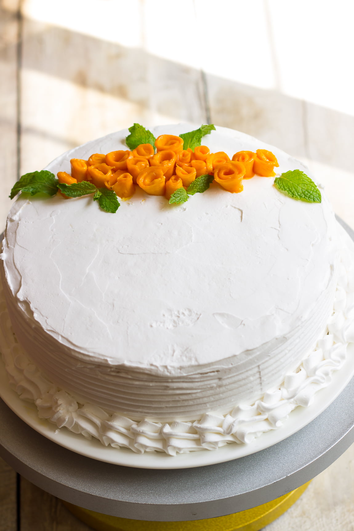 Mango rose cake served on a plate with a dollop of whipped cream