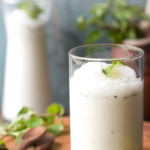 Glass of chilled masala buttermilk garnished with coriander and cumin