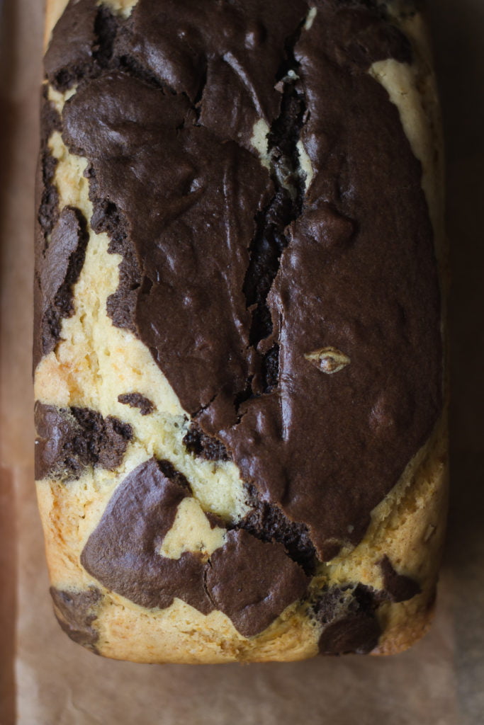 Whole chocolate marble cake on a cooling rack with knife beside