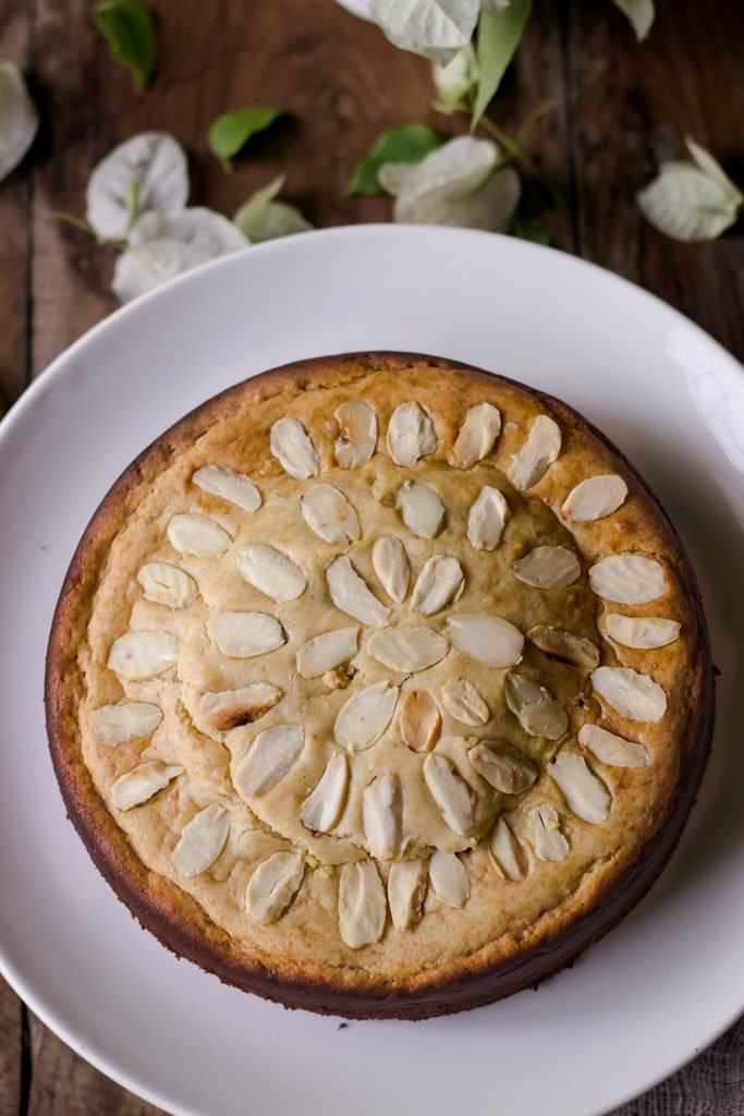 A whole Eggless Mawa Cake garnished with chopped nuts on top