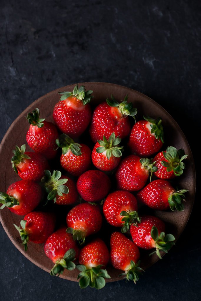 Overhead shot of strawberries arranges beautifully in a wooden bowl