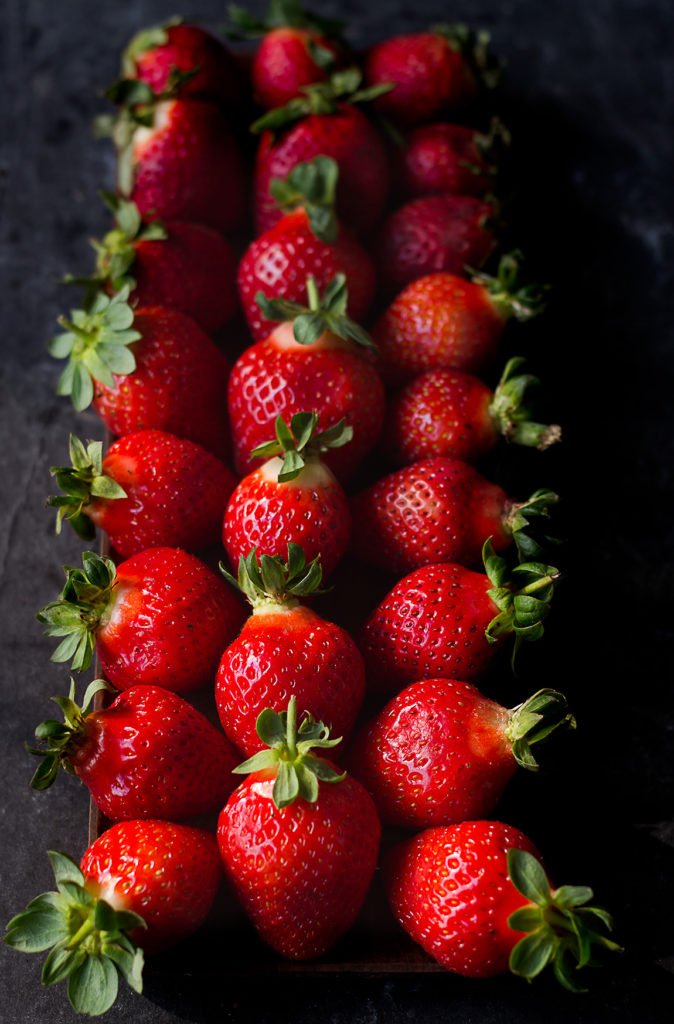 Strawberries arranged in a queue on a wooden table