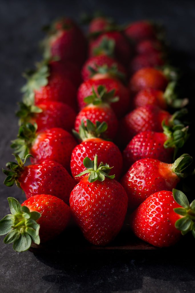 Strawberries with bright red color, a natural sheen, and fresh green caps on top
