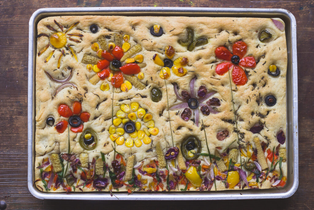 Close-up of the vegetable arrangement, creating a garden-like design on the focaccia
