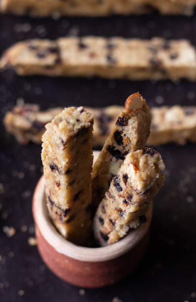 Biscotti placed in a glass jar with almonds scattered around