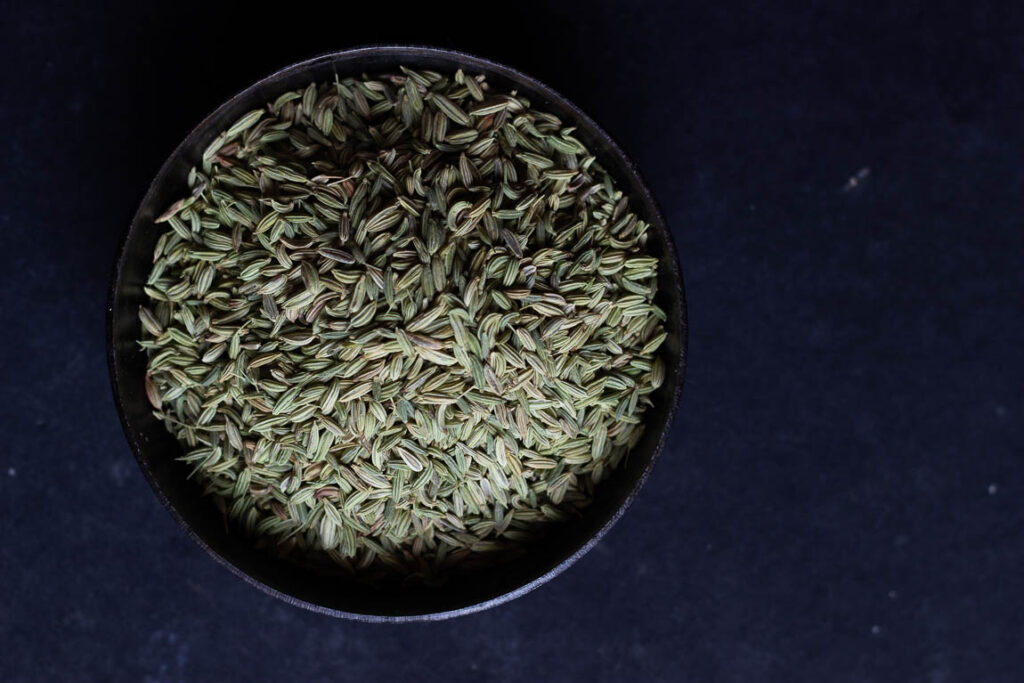 Golden-brown roasted coriander seeds cooling in a plate