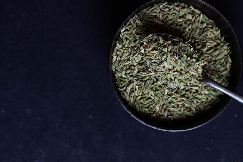 Close-up view of funnel seeds in a bowl with the spoon inside it