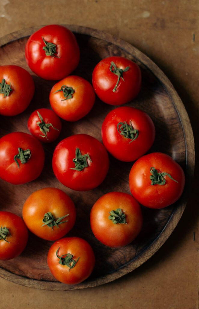 Ripe tomatoes placed on a wooden tray, ready to be sun dried
