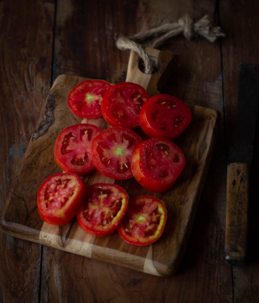 Sliced tomatoes spread evenly on a baking sheet for sun drying