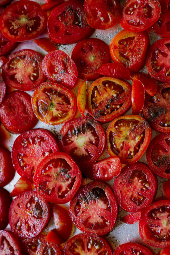 Salt and herbs sprinkled on sliced tomatoes for seasoning