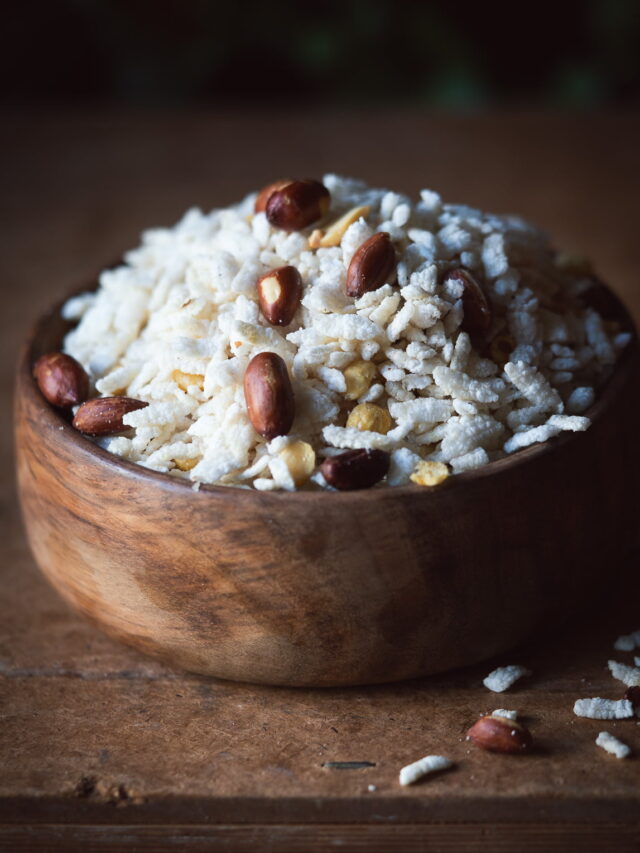 A bowl of freshly prepared Poha Chivda Namkeen garnished with curry leaves and peanuts