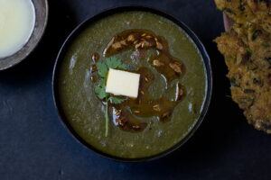 A bowl of rich and creamy Sarson Ka Saag topped with butter, served hot in Punjabi style