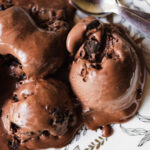 Homemade chocolate ice cream being scooped from a freezer-safe container