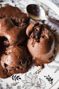 Homemade chocolate ice cream being scooped from a freezer-safe container